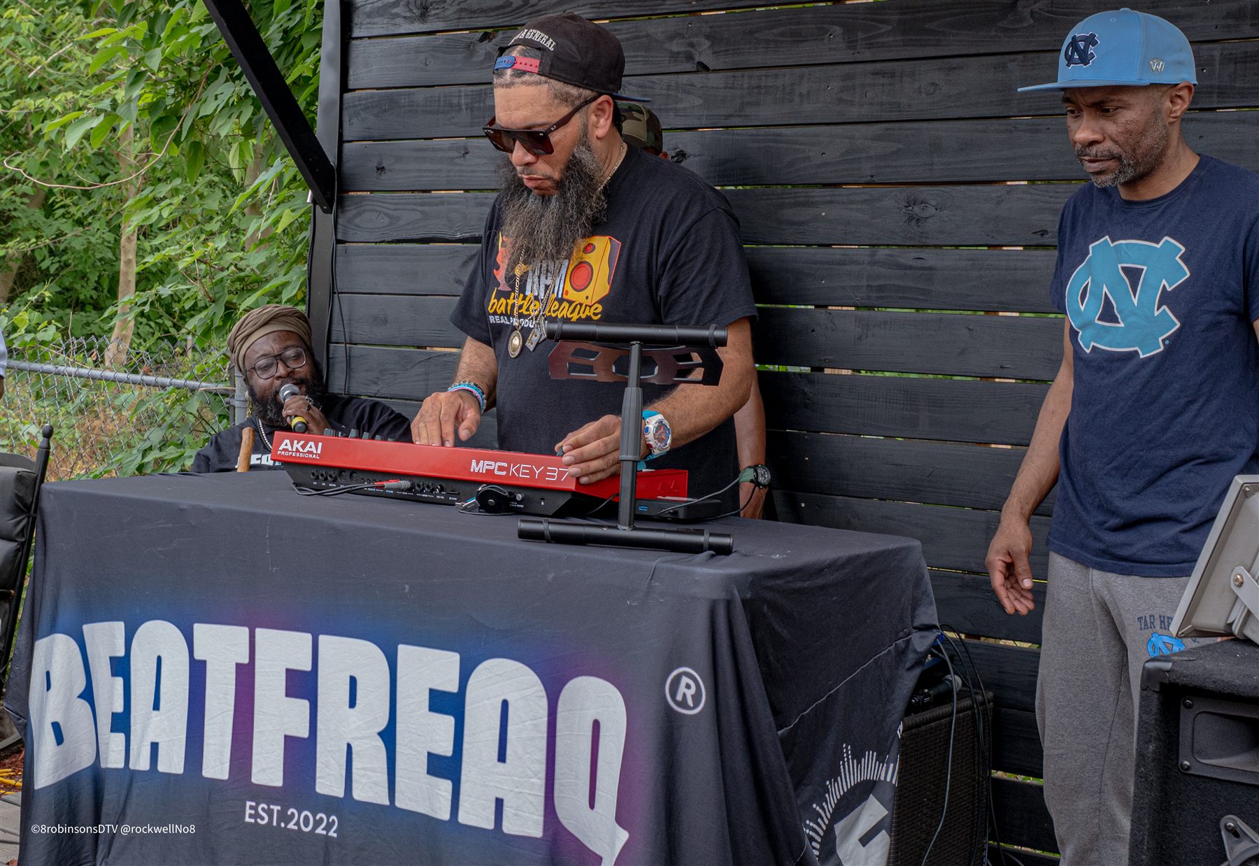 A producer plays a keyboard at a table draped with the Beat Freaq banner