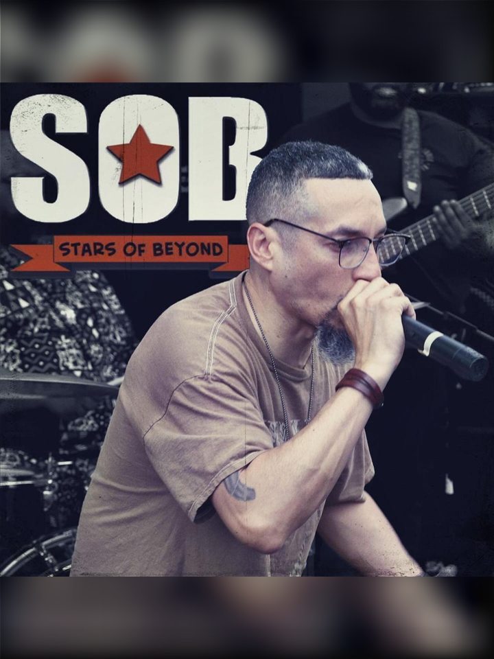 An MC on the mic in front of the Stars of Beyond logo, 2024.