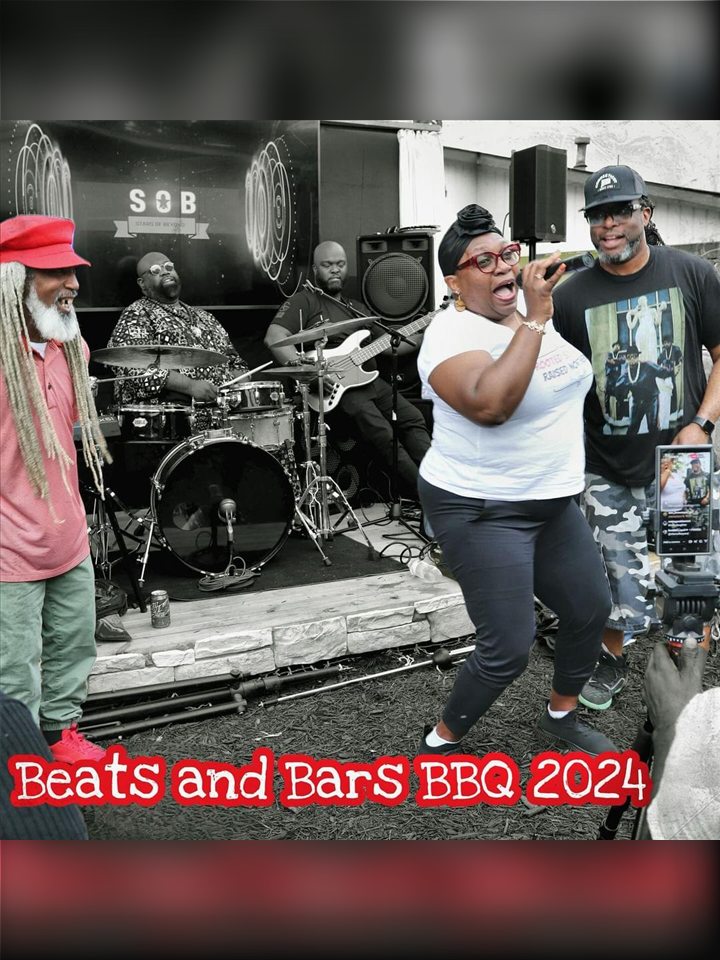 A singer and an MC with the live band behind them, 2024.