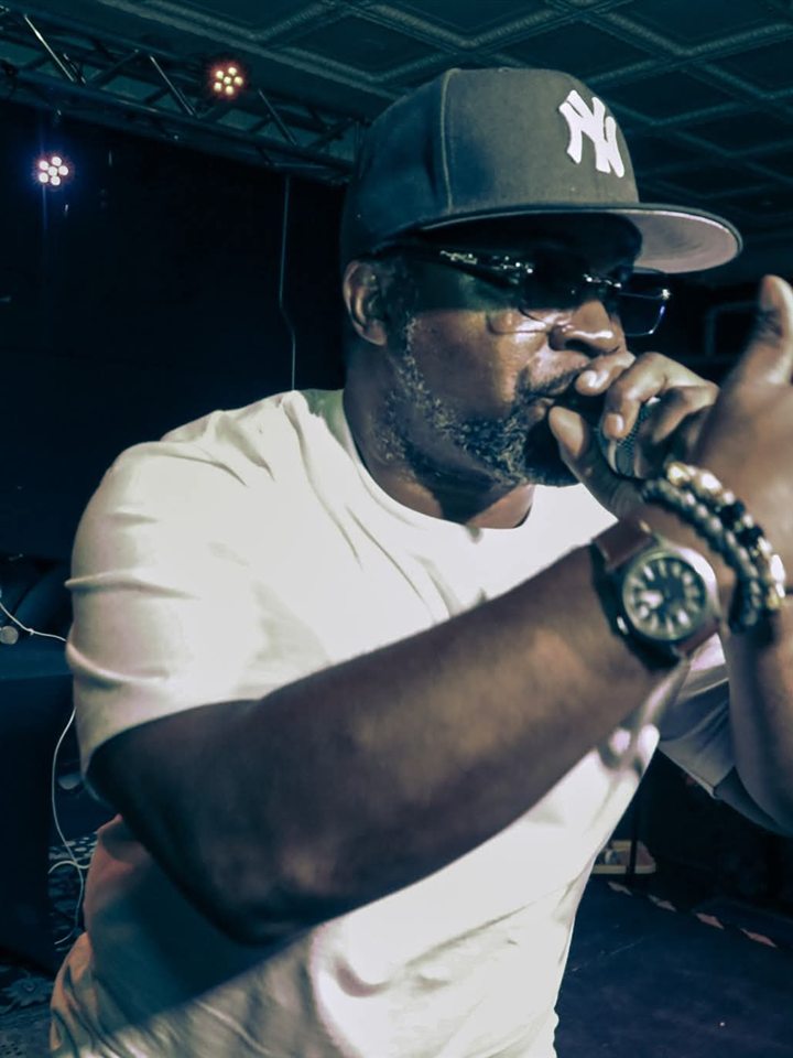 An MC in a Yankees cap on the mic, 2025.