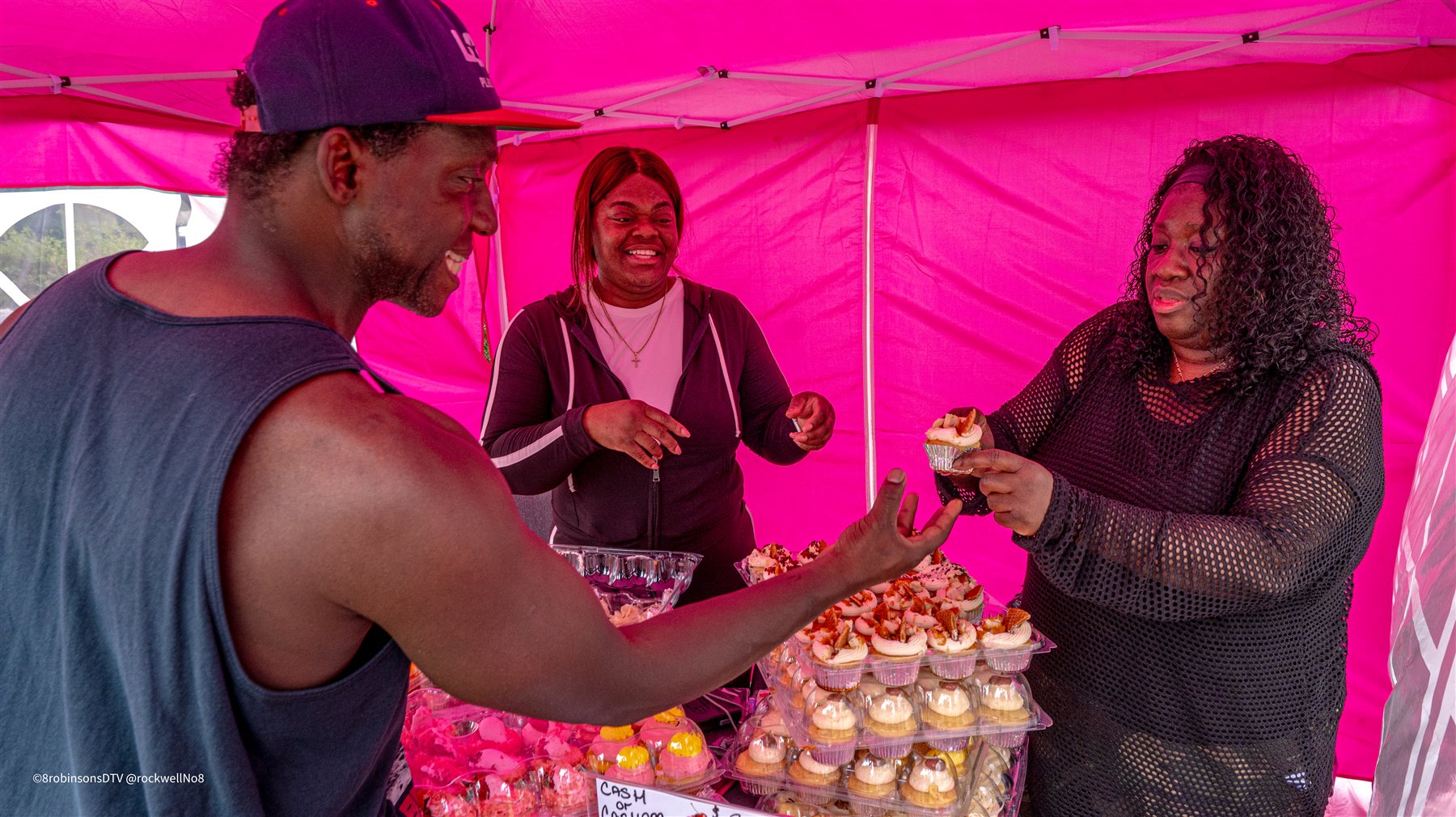 Tara Edwards hands a cupcake to an attendee inside the Let Them Eat Cupcakes tent at Beats & Bars Barbecue, 2026.